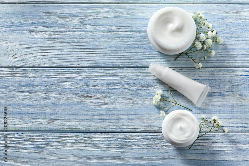 Flat lay composition with skin care cosmetics and flowers on wooden background Flat lay composition with skin care cosmetics and flowers on wooden background