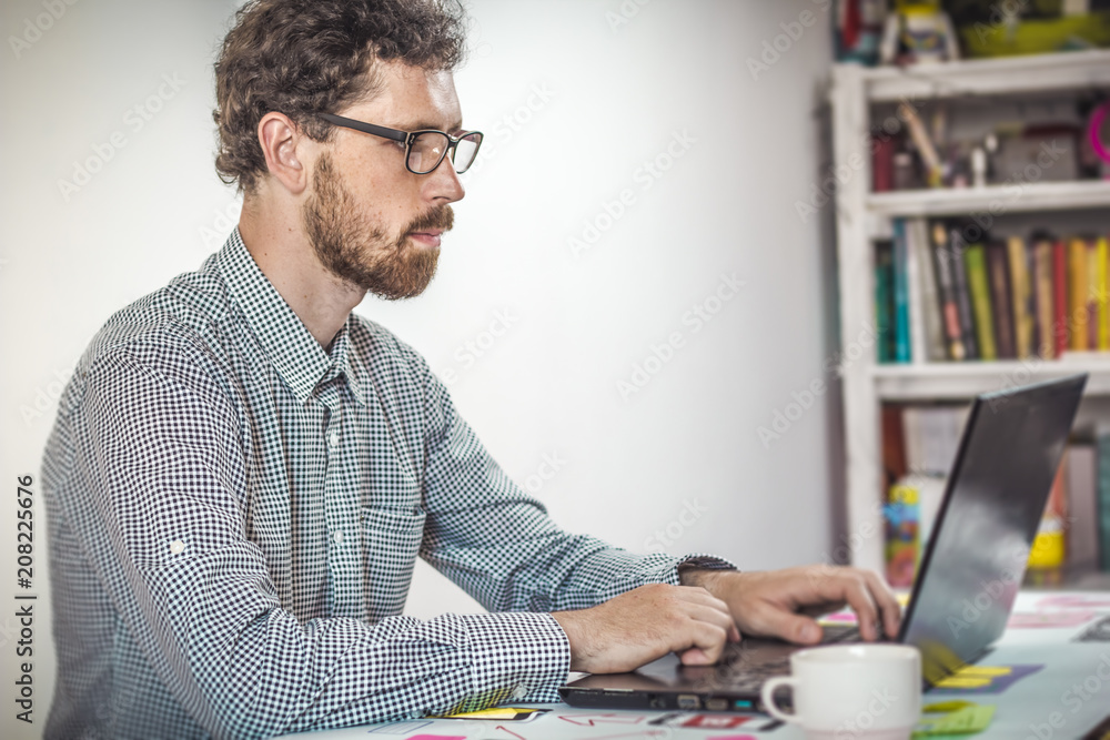 Freelancer works for a laptop in the workplace. A modern young man uses a computer. Freelancer works for a laptop in the workplace. A modern young man uses a computer.