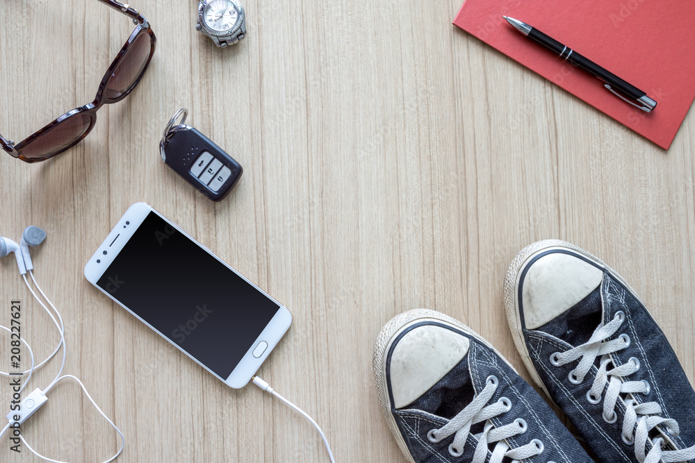 Flat lay traveler accessories on wooden floor background with remote car, smartphone, earphones , pen, paper note , shoes and sunglasses. Top view travel or vacation concept. Flat lay traveler accessories on wooden floor background with remote car, smartphone, earphones , pen, paper note , shoes and sunglasses. Top view travel or vacation concept.