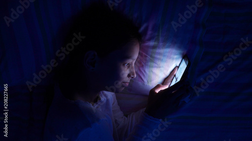 digital modern device addiction. gadget night sleeplessness. young caucasian girl browsing chatting playing serfing network with tablet bed. mobile phone apps. photo