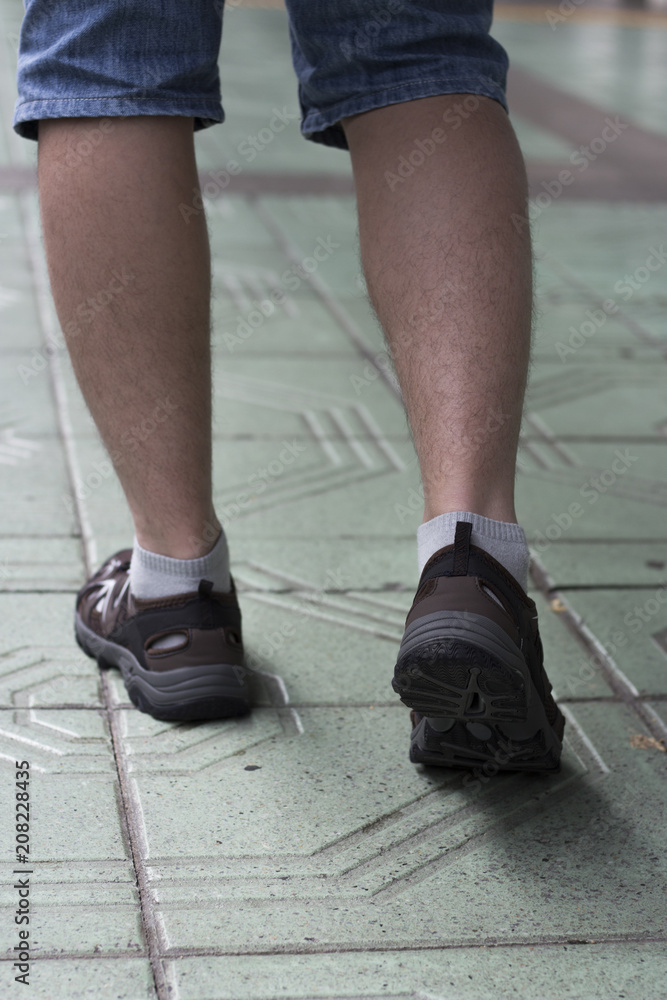 Male legs in sneakers view from behind, traveling, walking