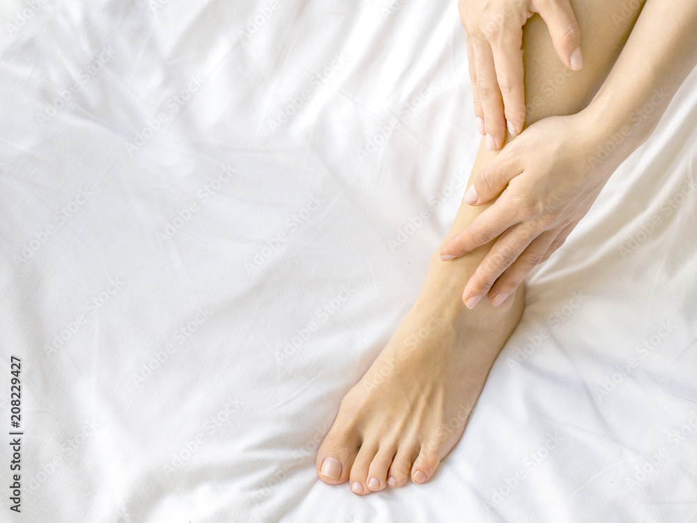 Young woman massaging her foot on the bed. Healthcare concept. Young woman massaging her foot on the bed. Healthcare concept.
