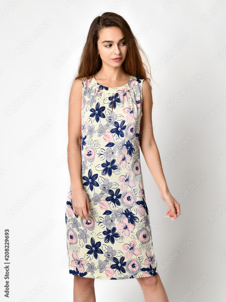 Young beautiful woman posing in casual summer dress with flowers on grey Young beautiful woman posing in casual summer dress with flowers on grey