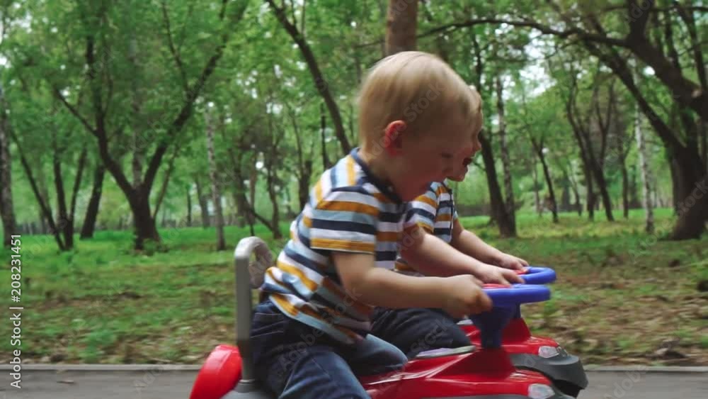 Little boys ride on their toy cars in the park. The competition of brothers in a children's car Little boys ride on their toy cars in the park. The competition of brothers in a children's car