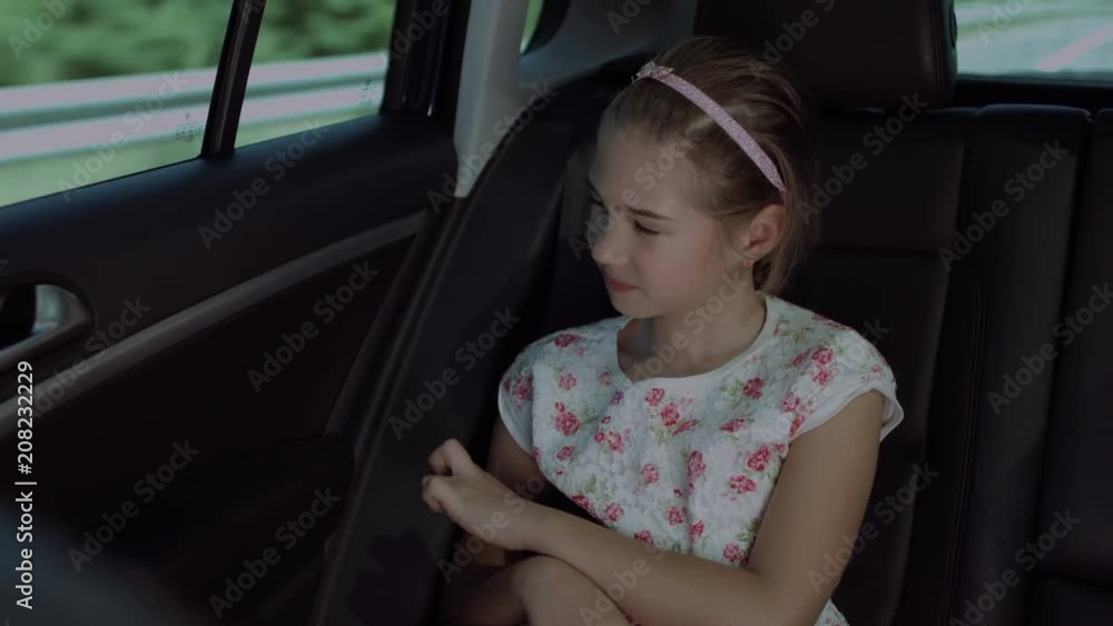 Sweet elementary age girl looking through car window while sitting in the back seat of the car during road trip. Cute thoughful child enjoying view from vehicle interior while travelling by car. Sweet elementary age girl looking through car window while sitting in the back seat of the car during road trip. Cute thoughful child enjoying view from vehicle interior while travelling by car.