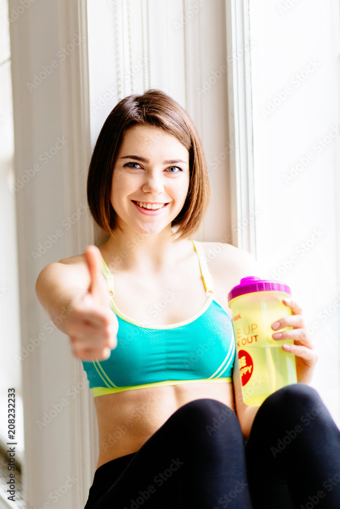 Pretty athletic girl with short brown hair showing ok..Young positive woman  giving a thumb up of approval while smiling at the camera in a health and fitness concept