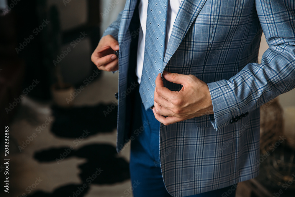 Close-up businessman groom wearing his blue checkered jacket at the morning of wedding day. Concept of men stylish elegance clothes.