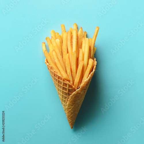 Fried potatoes in waffle cones on blue background. Hot salty french fries with tomato sauce. Fast food, junk food, diet concept. Top view. Minimal style. Pop art design, creative concept.