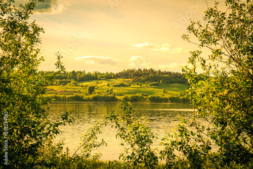 Fototapeta Naklejka Na Ścianę i Meble -  Sunset over lake and blossoming meadow.