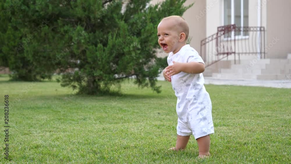 Funny toddler baby boy stay playfully during walk on backyard lawn Funny toddler baby boy stay playfully during walk on backyard lawn