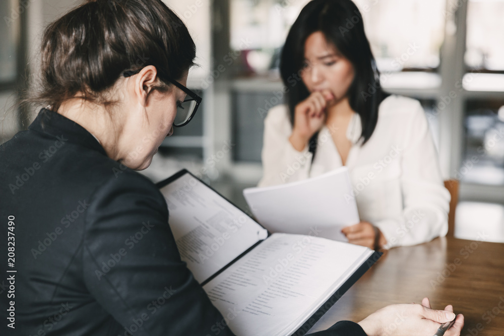 Photo from back of businesswoman interviewing, and talking with nervous female applicant during job interview - business, career and placement concept Photo from back of businesswoman interviewing, and talking with nervous female applicant during job interview - business, career and placement concept