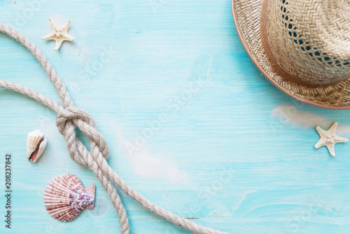 Marine rope and straw hat are on the blue wooden background