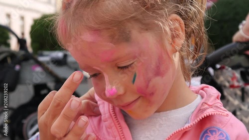 Painting child girl face portrait body art after sprinkle colored powder festival photo