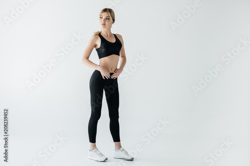 beautiful sportswoman in black sportswear standing isolated on grey