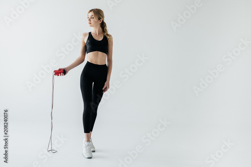 young sportive woman with skipping rope isolated on grey