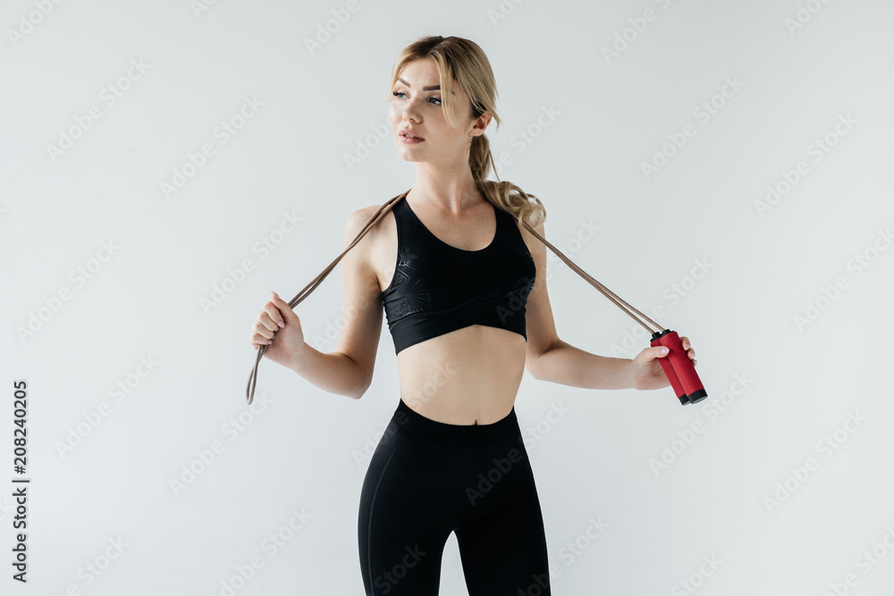 portrait of young sportive woman with skipping rope isolated on grey portrait of young sportive woman with skipping rope isolated on grey