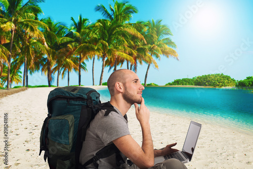 Explorer plans a new travel to a tropical beach with his laptop