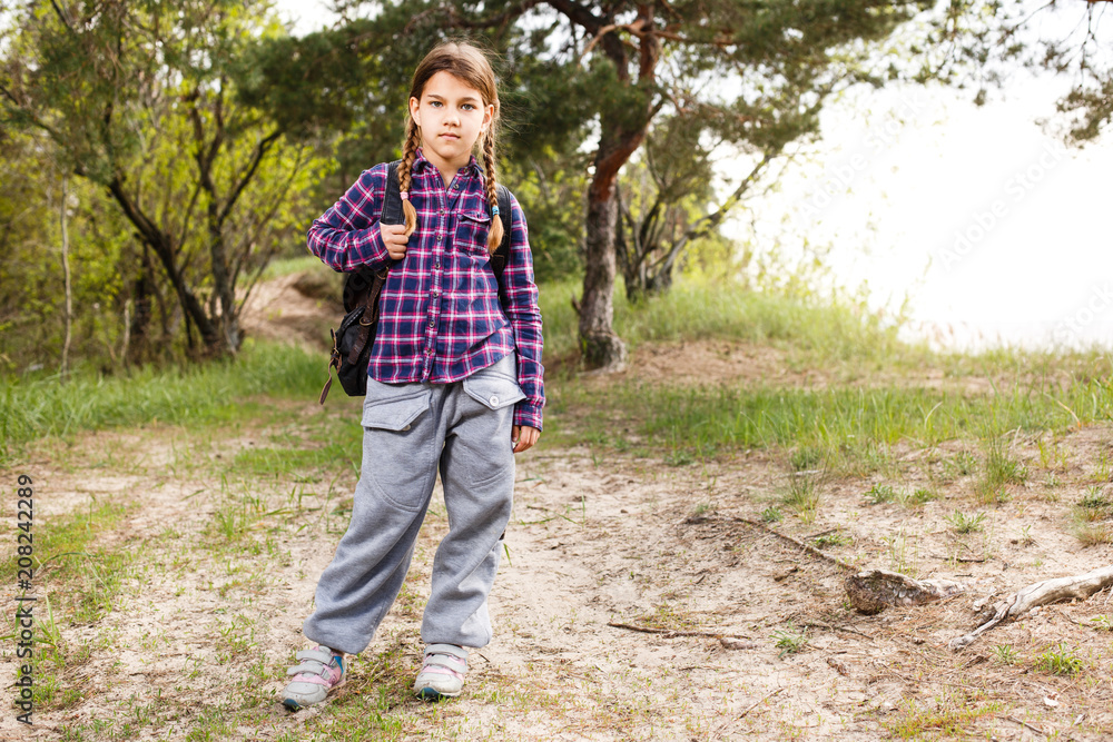 Little girl with backpack traveling in the forest Little girl with backpack traveling in the forest
