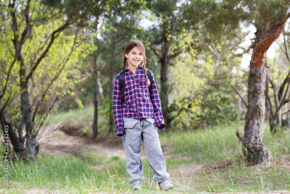 Little girl with backpack traveling in the forest Little girl with backpack traveling in the forest