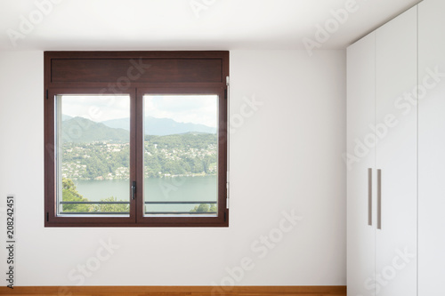 White empty room with windows overlooking the lake and large white wardrobe