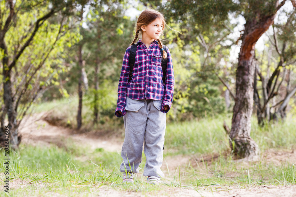 Little girl with backpack traveling in the forest Little girl with backpack traveling in the forest
