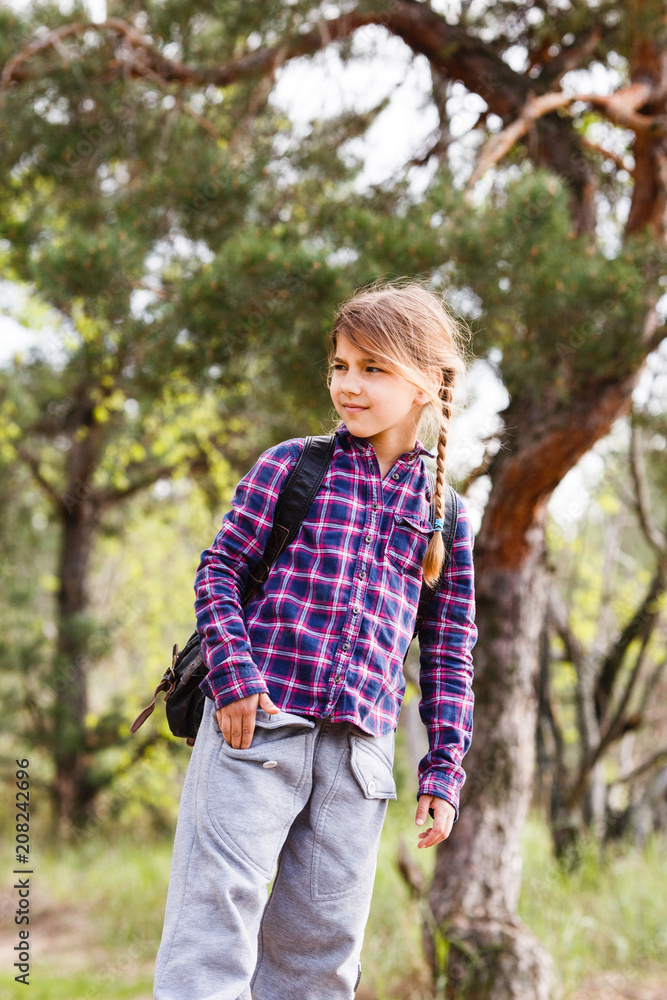 Little girl with backpack traveling in the forest Little girl with backpack traveling in the forest