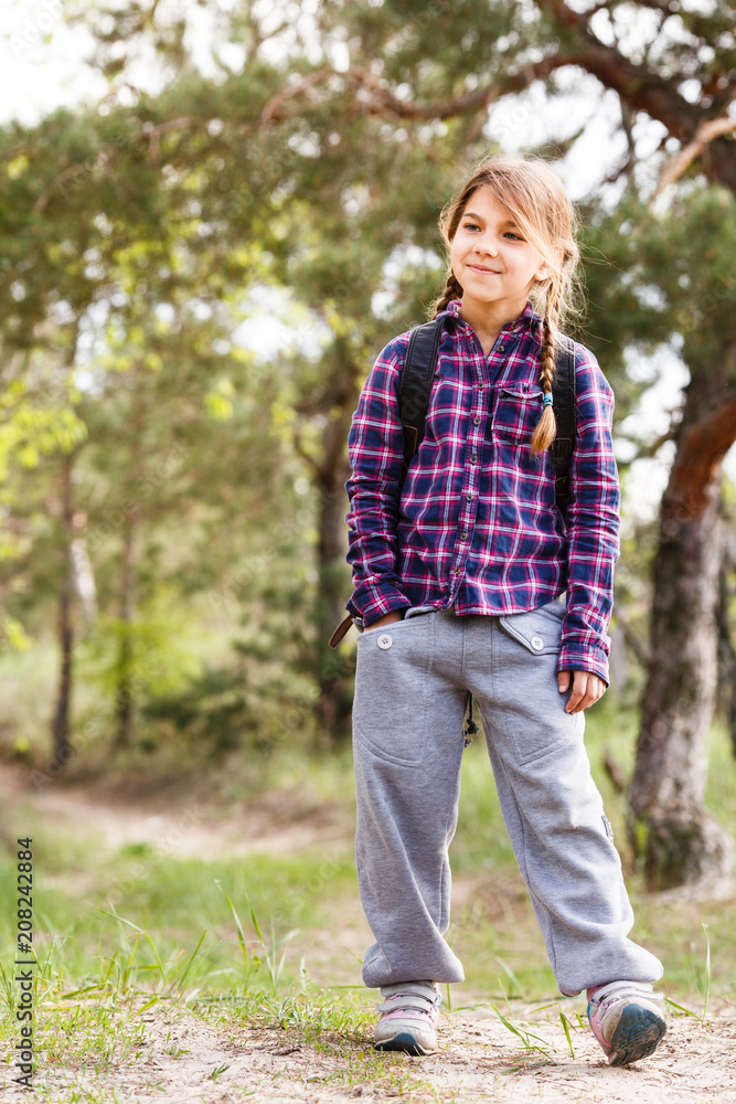 Little girl with backpack traveling in the forest Little girl with backpack traveling in the forest
