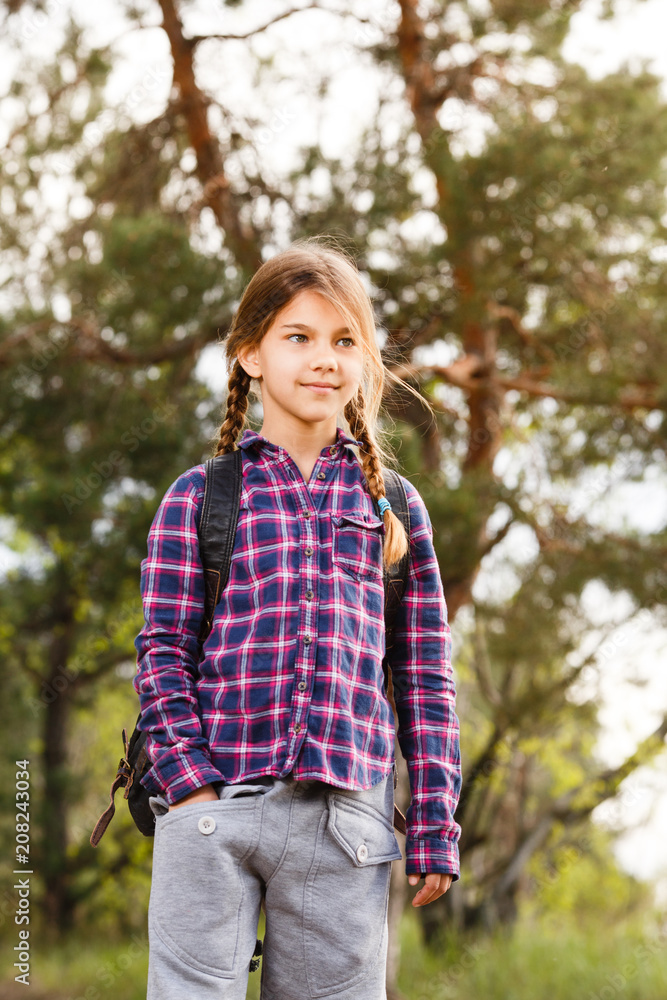 Little girl with backpack traveling in the forest Little girl with backpack traveling in the forest