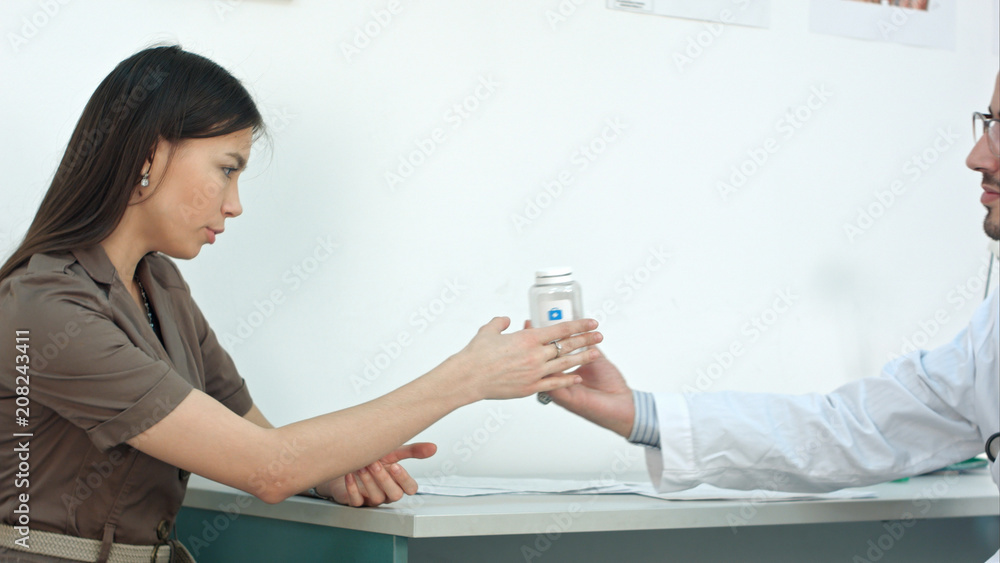 Male medical worker giving pills to worried woman patient Male medical worker giving pills to worried woman patient