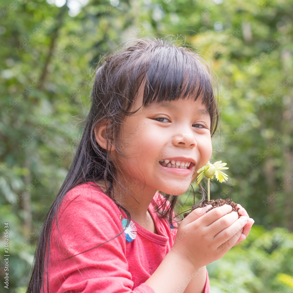 Kid holding young plant in hands against spring green background. Ecology concept Kid holding young plant in hands against spring green background. Ecology concept