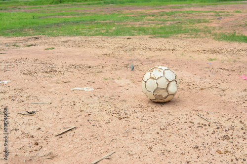 old white football on ground with brown soil and small rock