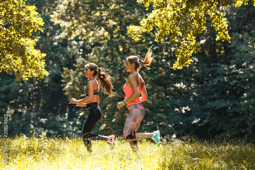 Two young female friends jogging at the woods.Green environment.