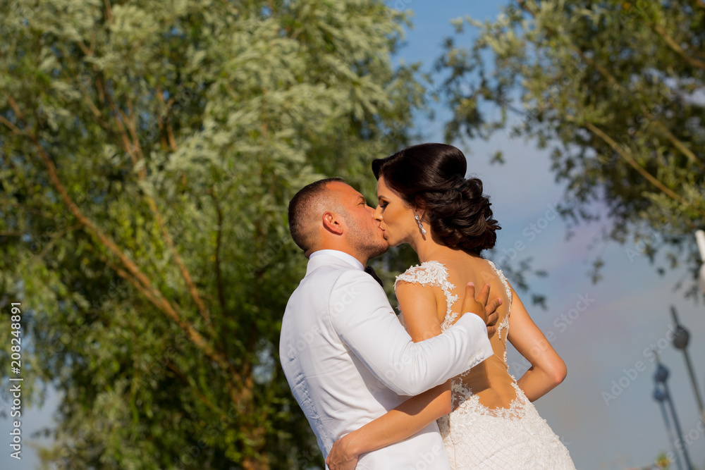 Fototapeta premium Beautiful Romantic Wedding Couple Of Newlyweds Hugging In Park On Sunset