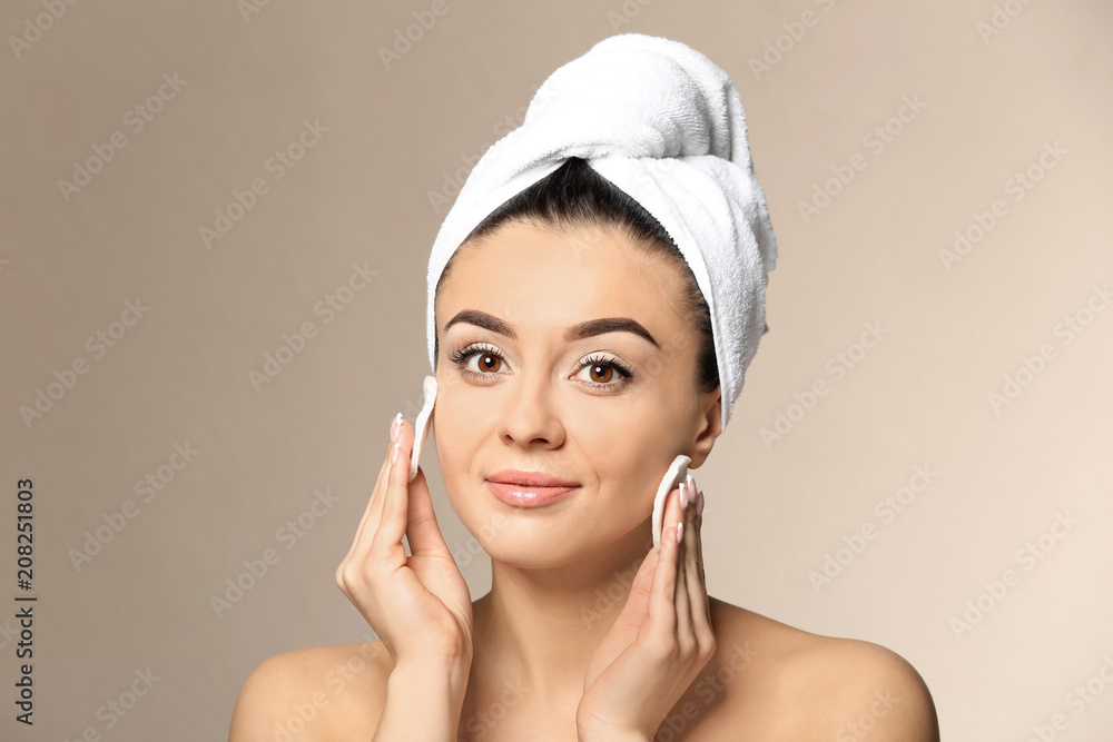 Beautiful young woman with silky skin using cotton pads on color background Beautiful young woman with silky skin using cotton pads on color background