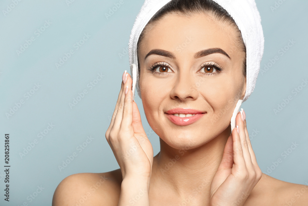 Beautiful young woman with silky skin using cotton pads on color background Beautiful young woman with silky skin using cotton pads on color background