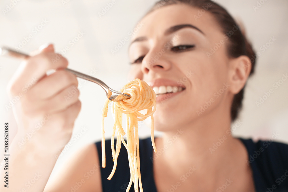 Fototapeta premium Young woman eating tasty pasta in restaurant