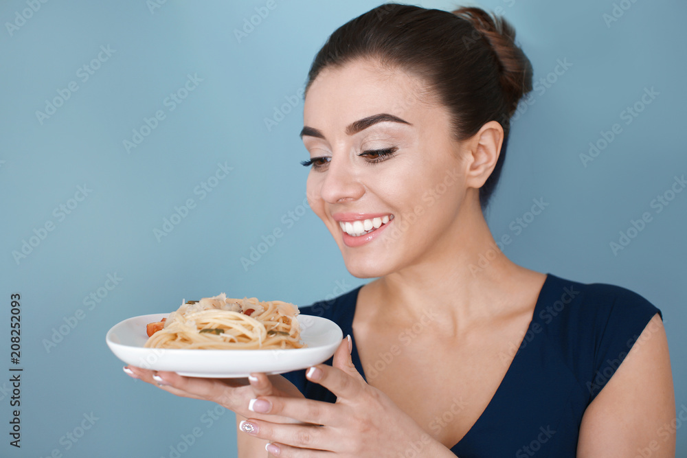 Young woman with plate of tasty pasta on color background Young woman with plate of tasty pasta on color background