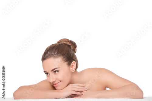 Beautiful young woman with silky skin after spa treatment lying on towel against white background