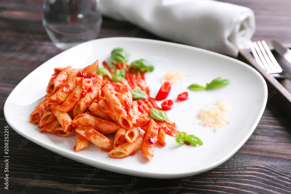 Plate with delicious penne pasta and sauce on table Plate with delicious penne pasta and sauce on table
