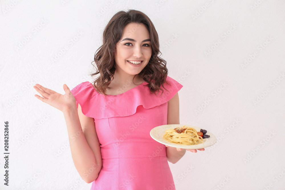 Young woman with plate of tasty pasta on white background