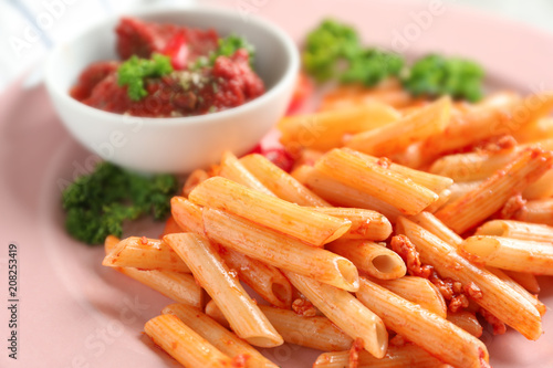 Tasty penne pasta with tomato sauce on plate, closeup