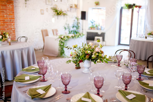 Wedding banquet, served tables with flowers and lots of greenery. © Alinsa