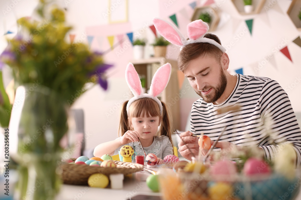 Father painting Easter eggs with his daughter at table Father painting Easter eggs with his daughter at table