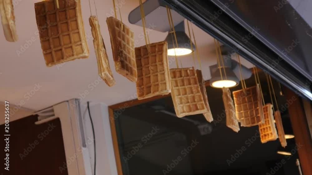 Suspended row of belgian waffles in street food point of sweets in