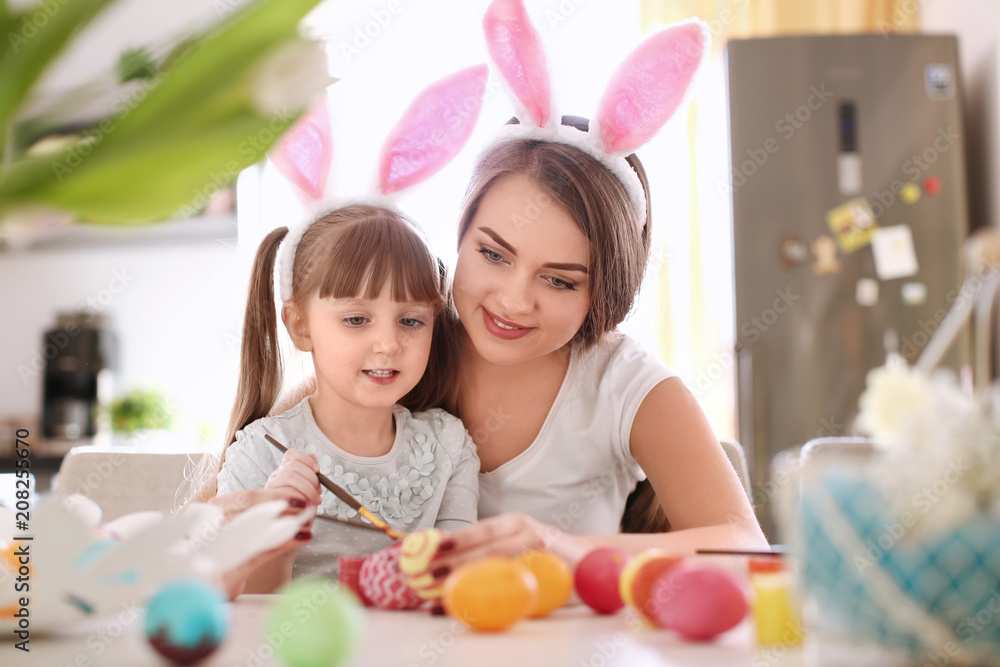Mother painting Easter eggs with her child at table Mother painting Easter eggs with her child at table