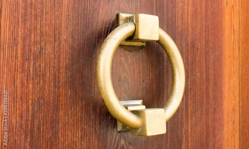 Close-up of typical Catalan brass door knocker married with veined wood with deep tones Close-up of typical Catalan brass door knocker married with veined wood with deep tones