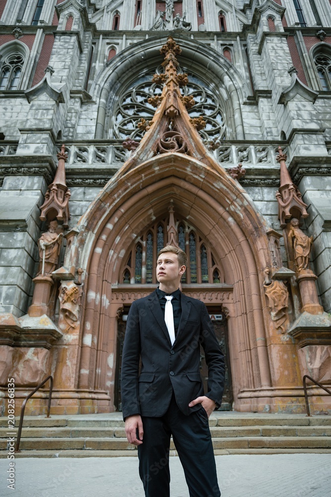 Fototapeta premium Handsome young man in trendy black suit and tie posing