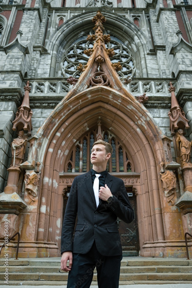 Handsome young man in trendy black suit and tie posing