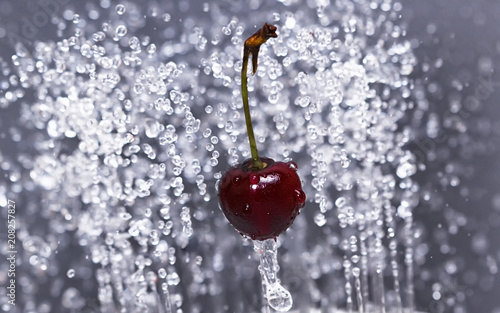 Fresh cherry on a gray background among the water