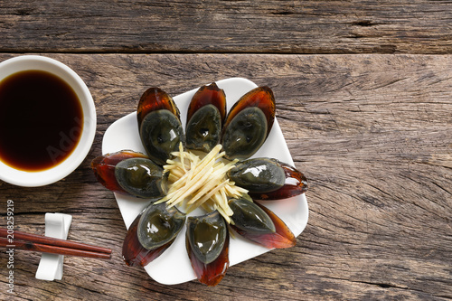preserved egg in a ceramic plate served with soy sauce on old wooden table, copy space for text. delicious appetizer menu photo